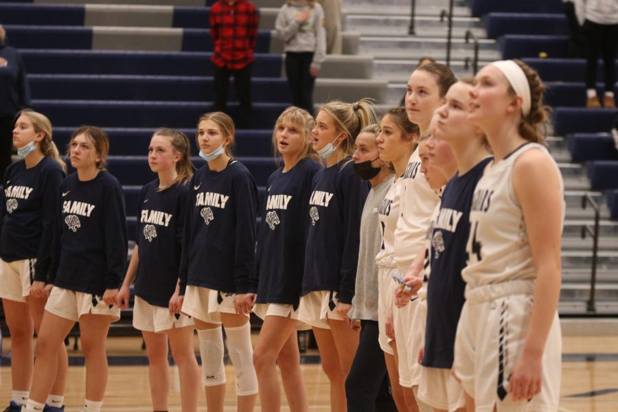 Holding hands, the girls basketball team sings the National Anthem.