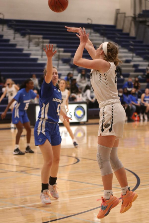 In the air, senior Emree Zars shoots a three pointer.