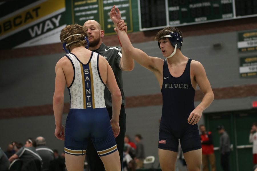 Hand raised in the air, junior Eddie Hughart is recognized for winning his match.