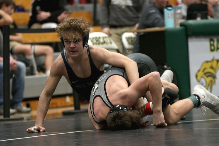 Looking to his coach for advice, sophomore Brady Mason works to pin his opponent.