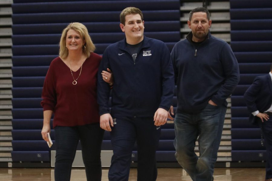 Walking onto the floor with his parents, senior Cole Seyb smiles towards the crowd.