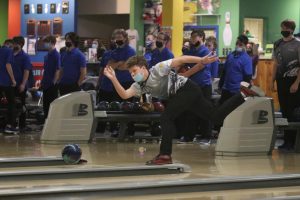 With his foot in the air, sophomore Austin Leiker rolls the ball toward the pins. 