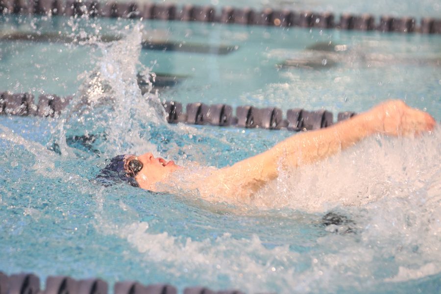 Competing in the men’s 200 medley relay, senior Derek Long swims the backstroke Saturday, Jan. 22. The relay team finished with a time of 2:10.89.
