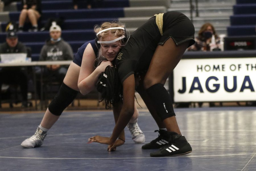 With her hands on her opponent’s head senior Rylee Allen-Atchison attempts to push her down on the mat. 