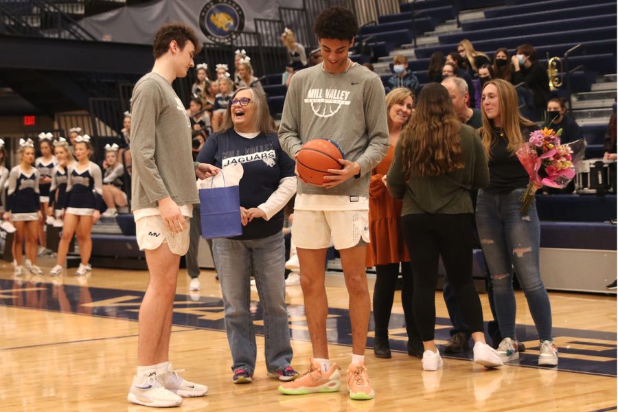 Looking at the ball giften to him by his underclassman teammates, senior Adrian Dimond smiles while accompanied by his mom. 