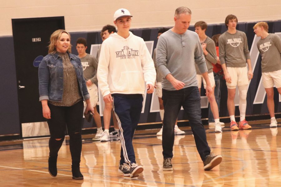 Walking side by side with his parents, senior Brendan Akehurst looks to his friends in the stands. 