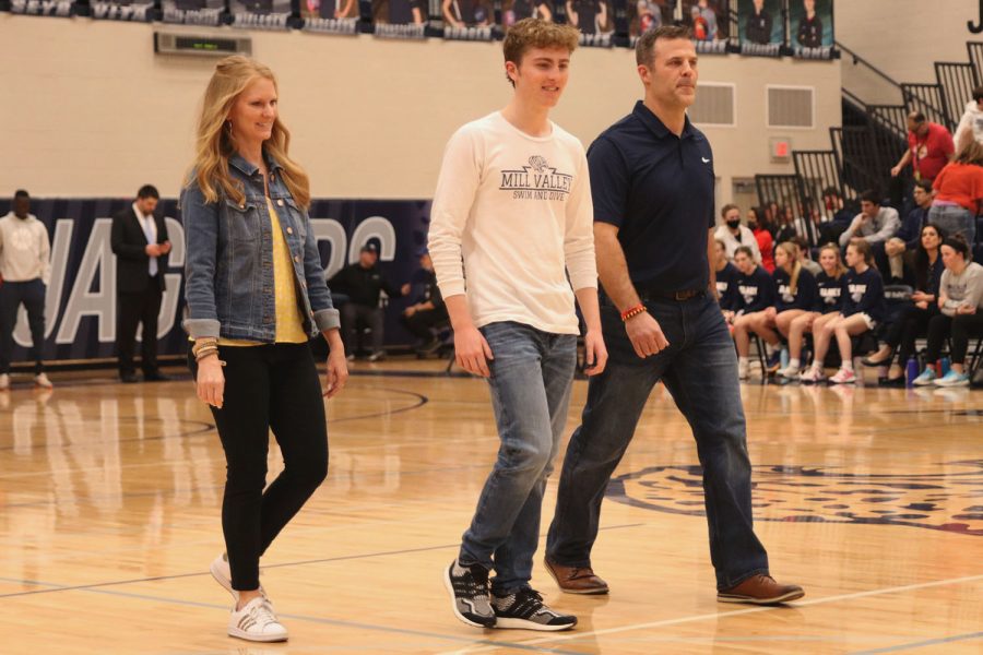 Looking at the people announced before him, senior Derek Long walks besides his parents. 