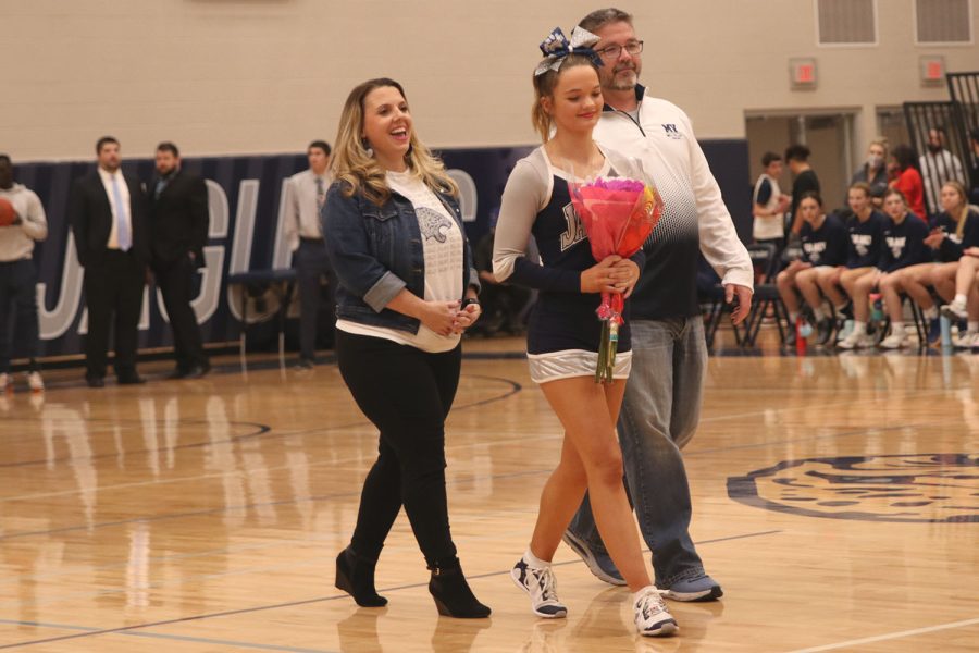 While her name is being announced, senior Rheagan Handy walks with her parents. 
