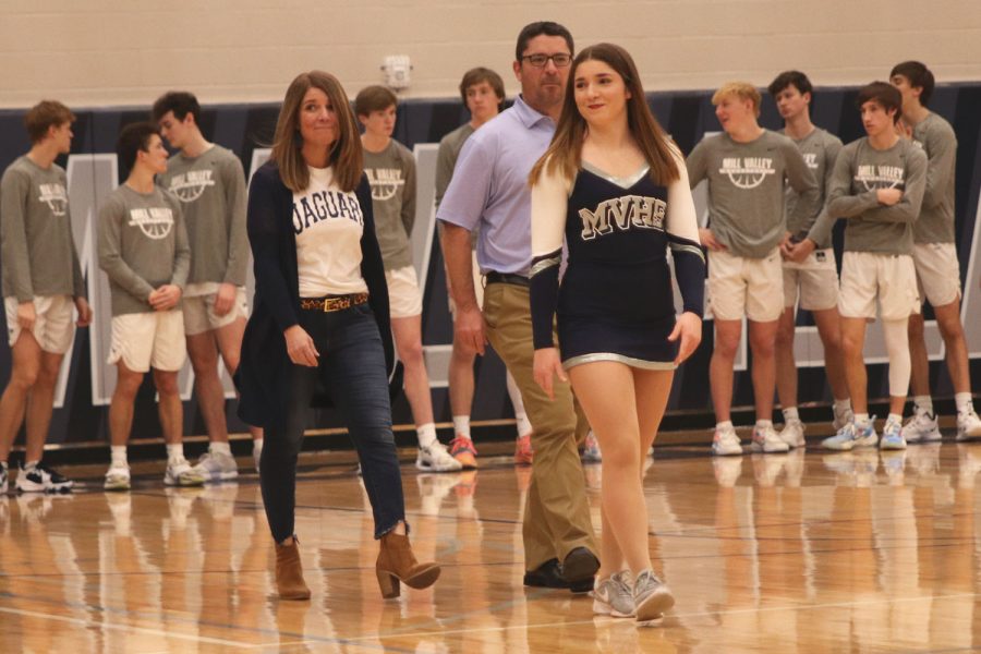 As she looks to her friends in the crowd, senior Anna Brazil walks onto the court accompanied by her parents. 