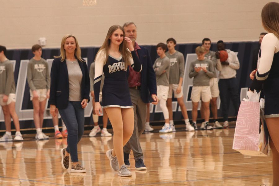 Looking to her teammate, senior Ella Lorfing walks alongside her parents.