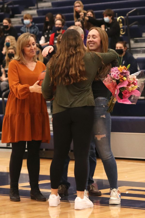While holding flowers, senior Paiten Griffith smiles and hugs junior Torri Olivarez. 