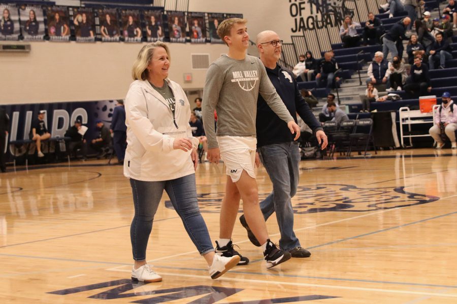 Walking besides his parents, senior Jackson Van Dyke walks onto the court.