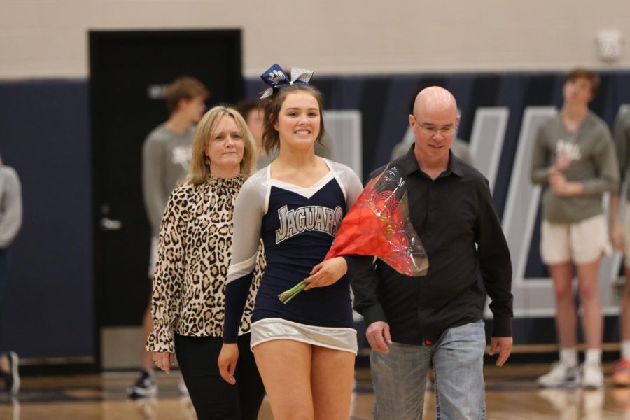 With a bouquet of flowers in her hand, senior Shelby Easum walks across the court to be recognized as a cheer senior.