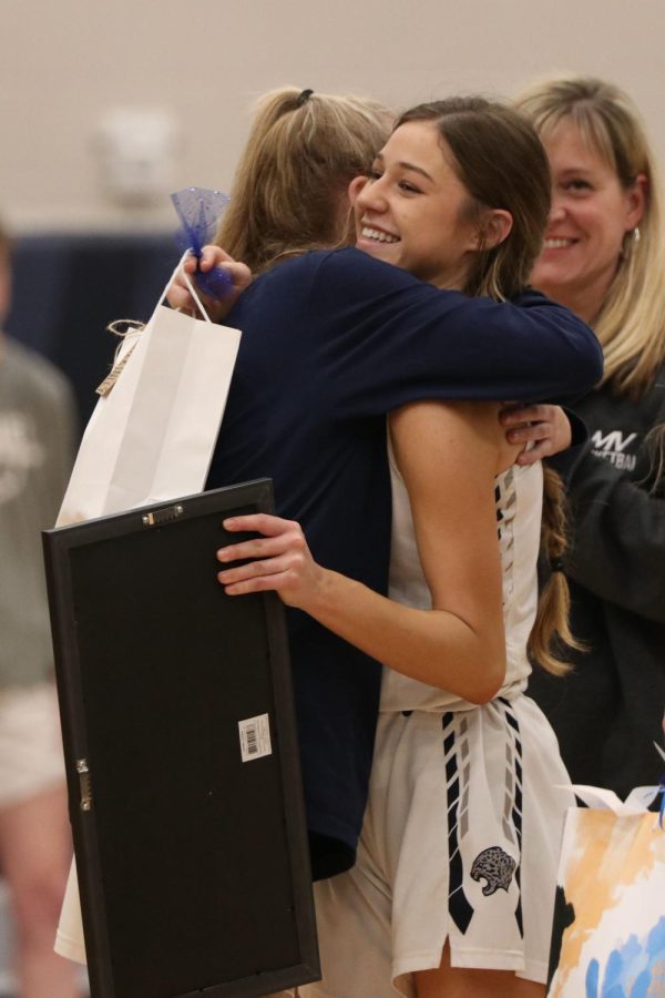 Hugging her teammate, senior Mackinley Fields accepts her senior gift. 