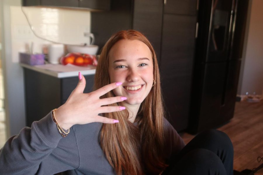 Posing with her finished nails, freshman AnnMarie Geise shows off the skills of her friend freshman Wren Altis.