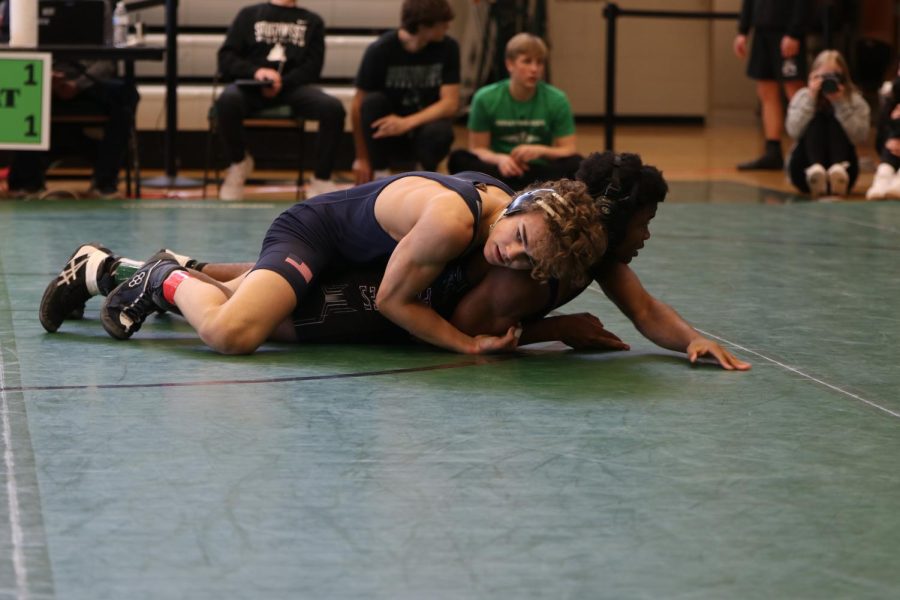 Looking to his coaches corner for advice, sophomore Brady Mason attempts to pin his opponent.
