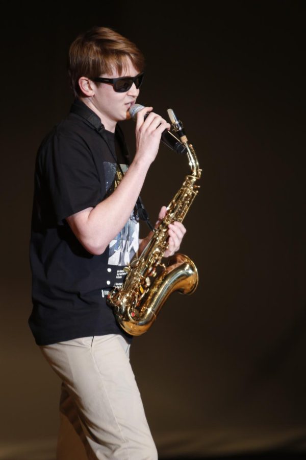 Wearing sunglasses, junior Brody Shulda sings and plays Stevie Wonders Sir Duke on the saxophone.