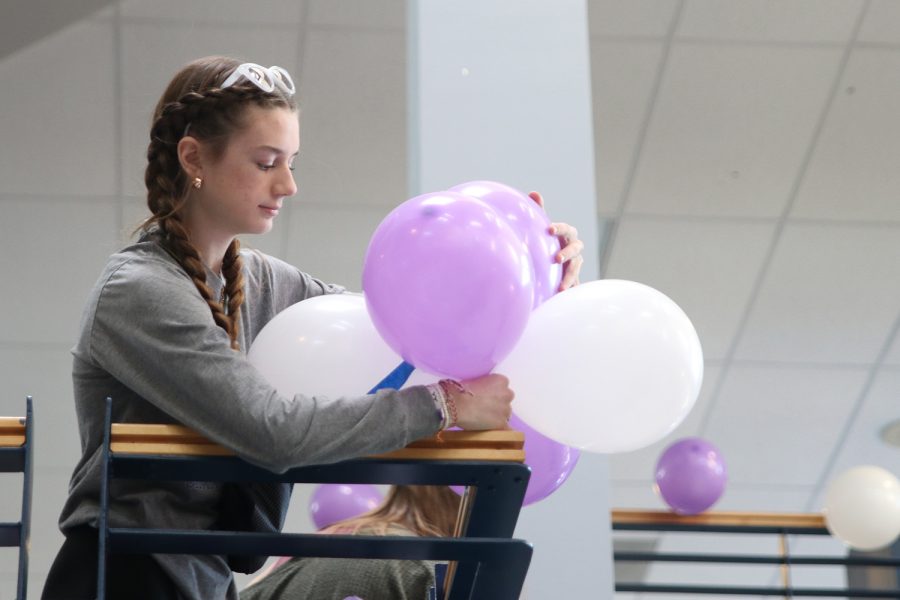 Taping balloons, freshman Seville Skinner helps decorate the stairway Monday, Feb. 21.

