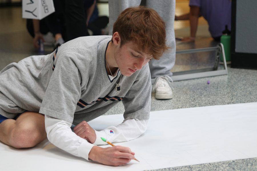 Writing, junior Sonny Pentola helps make a banner Monday, Feb. 21 for Relay for Life’s annual purple bomb. 
