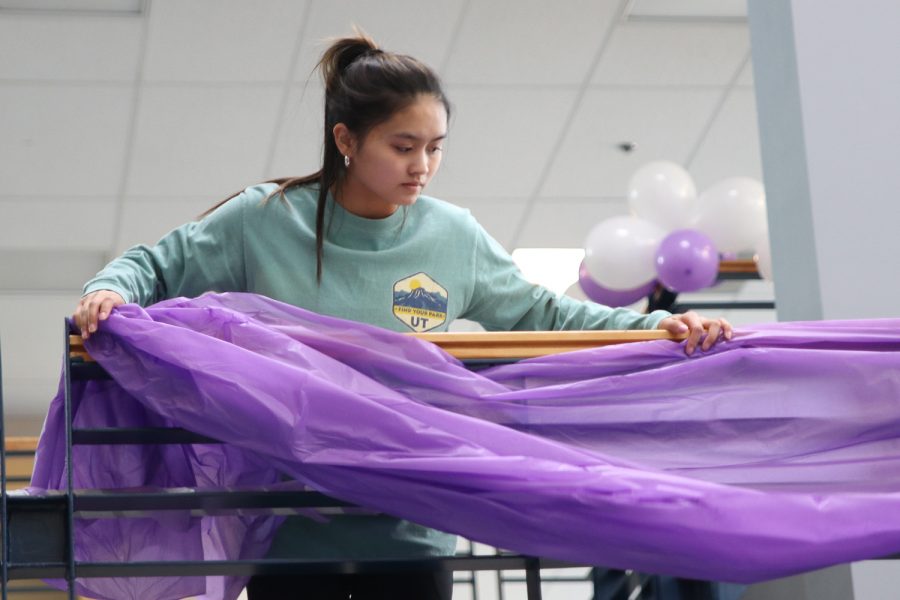 Focusing, senior Jada Eggelston wraps a table cloth around the stairs to help decorate the foyer Monday, Feb. 21.
