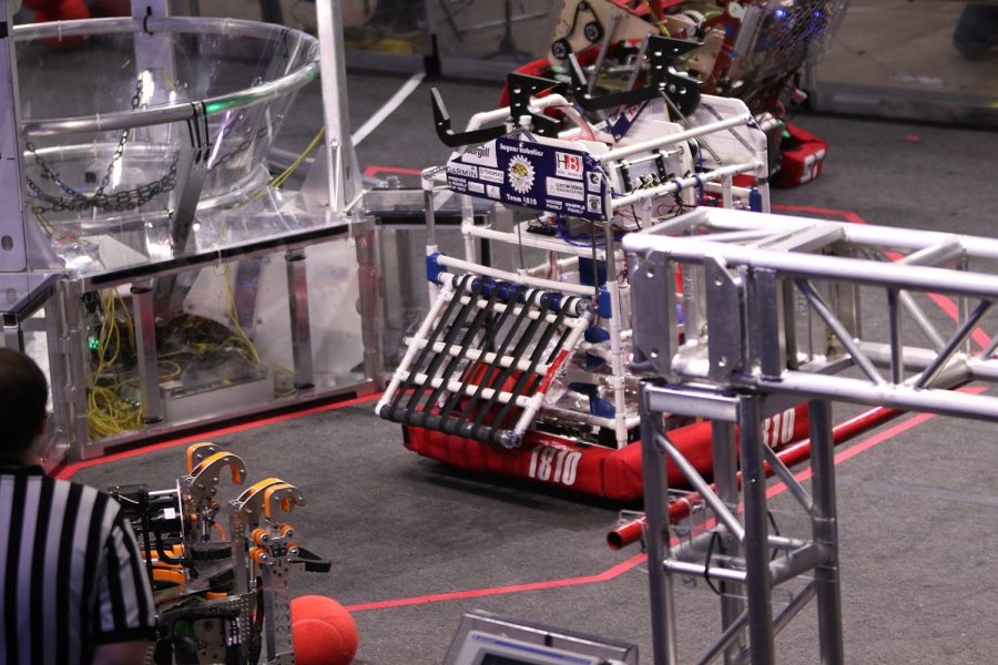 Using its side panel, the robot reaches to slide a ball into its center while competing for the red alliance. 