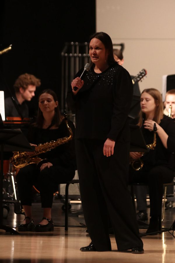 Talking to the crowd, band director Deb Steiner explains what music the band will play.