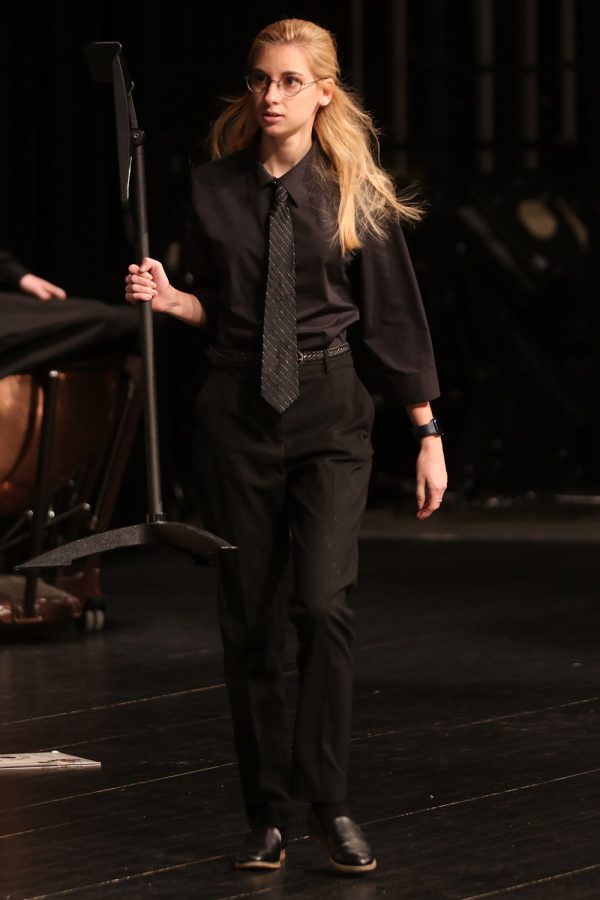 Lifting up the music stand, senior Ellie Basgall helps out clean after the concert is done. 