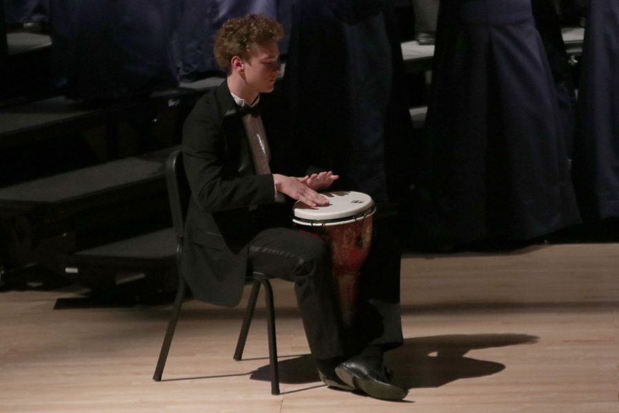 As he bangs the drum, junior Finn Campbell listens to the choir sing. 