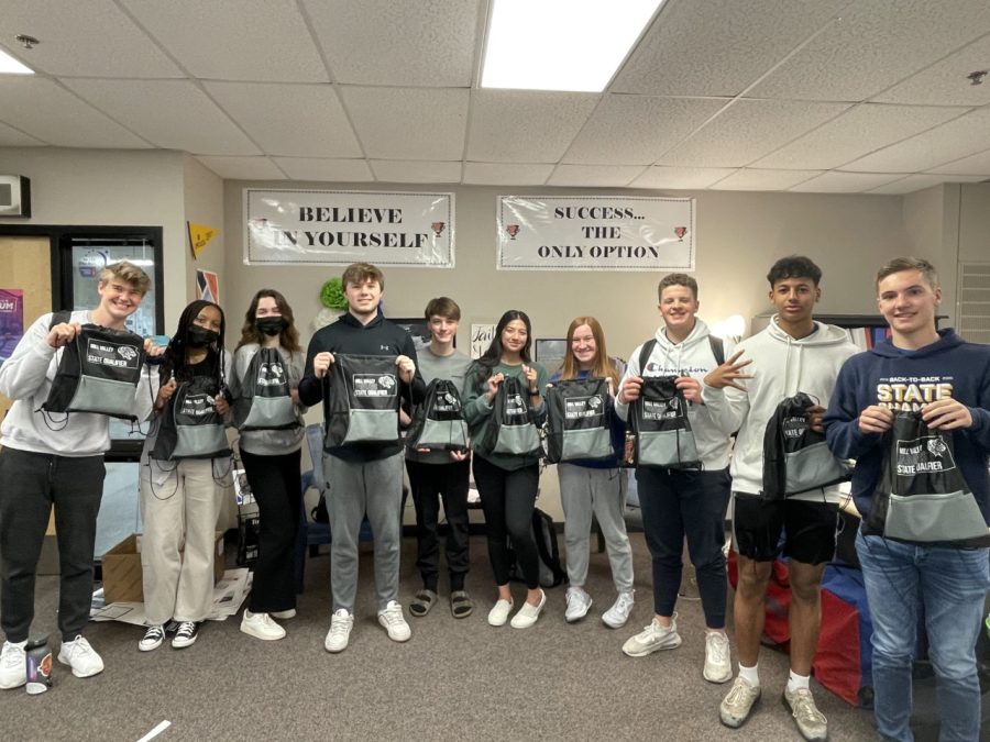 The deca team holding up their bags that they got for qualifying for state. 
