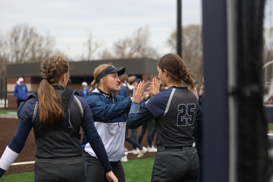 Junior Macee Moore high fives her teammates during the starting lineup before taking her place on the field.