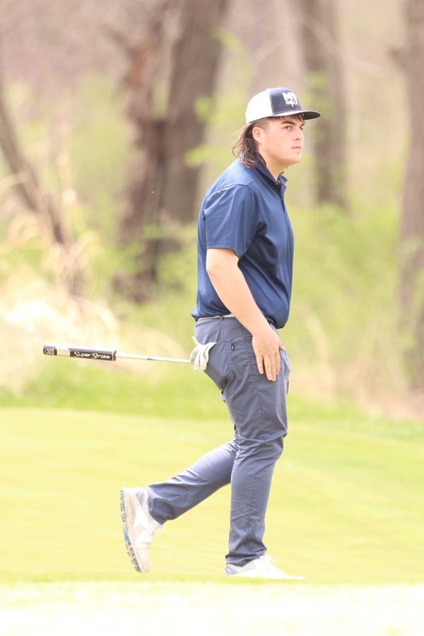 With a golf club in his hand, junior Karson Chalupnik walks to his golf bag to put his club away. Chalupnik went on to score 87 points at Falcon Lakes Golf Club Invitational Monday, April 11.