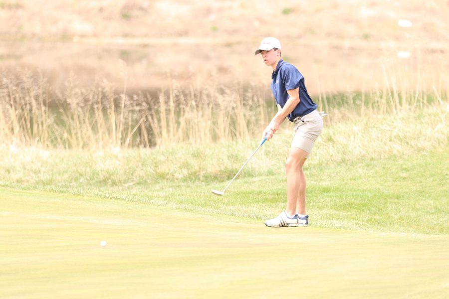 Eyes on the ball, junior Codey Geis stays still while watching the golf ball roller closer to the hole. Geis finished with a final score of 85 at Falcon Lakes Golf Club Invitational Monday, April 11.
