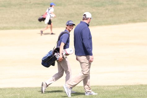 Walking beside each other, senior Brock Olson and head coach Drew Walters talk while they walk to the golf ball. Olson finished with a final score of 87 at Falcon Lakes Golf Club Invitational Monday, April 11.
