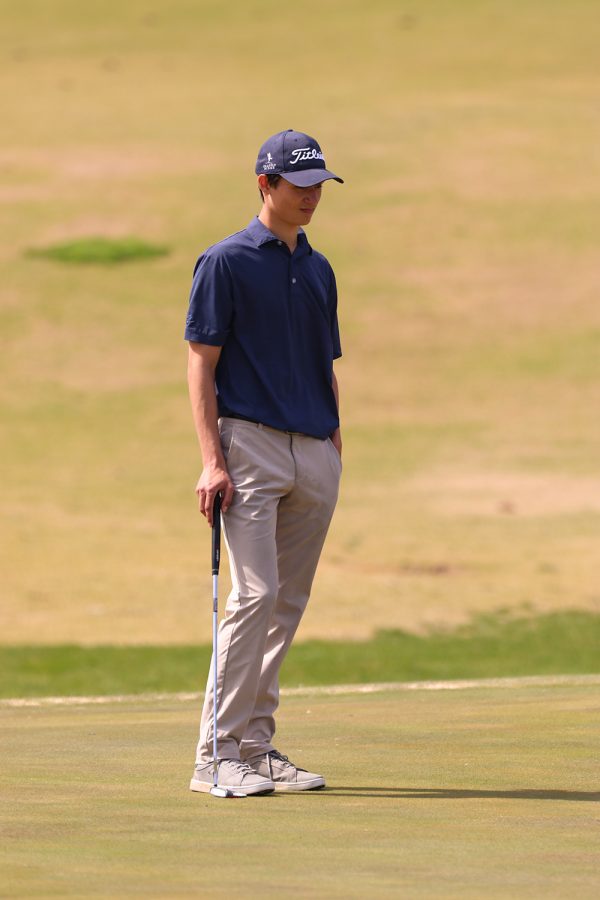 Waiting for his turn, senior Brock Olson observes his opponents while they putt.