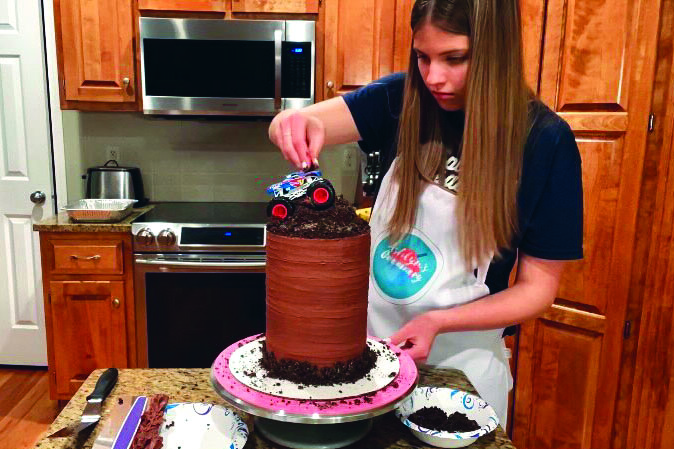 Placing a toy truck, sophomore Ashlyn Bellmyer puts the finishing touches on her order for a monster truck cake Tuesday, Jan. 25th.