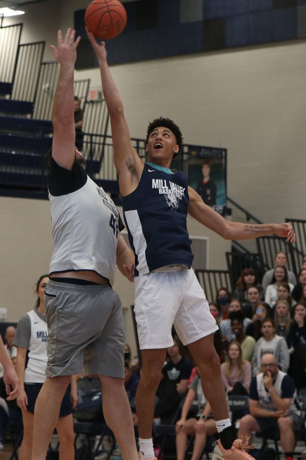 At the beginning of the student versus faculty basketball game, senior Adrian Dimond reaches up to gain possession of the ball.