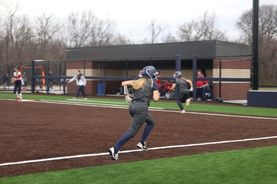 While Olathe North chases the ball, junior Haley Bryant sprints toward the home plate.