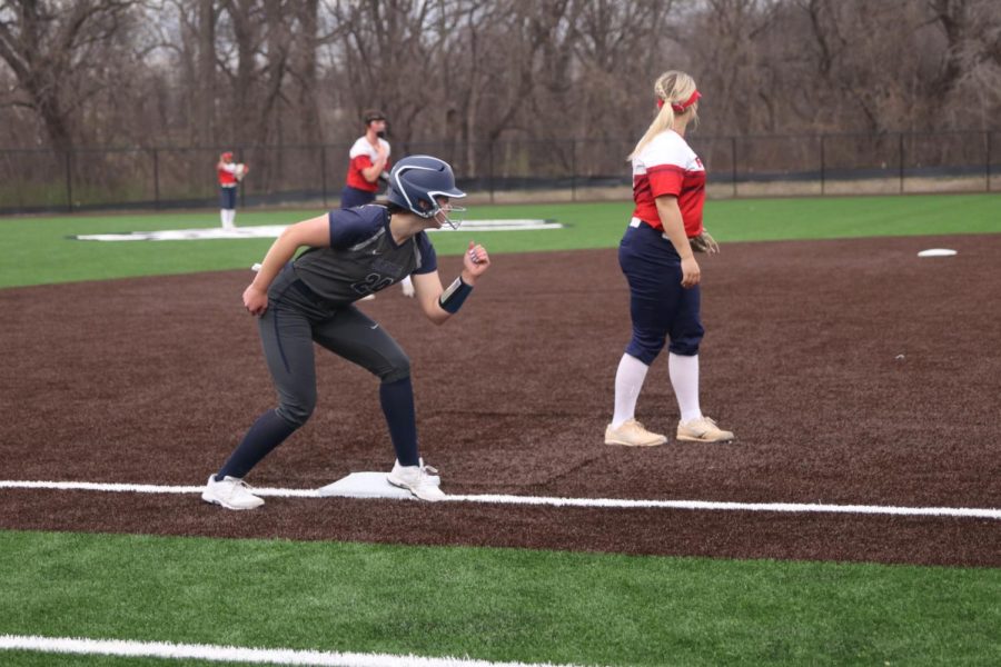 Standing on third base, junior Adisyn Hopkins prepares to run toward the home plate.