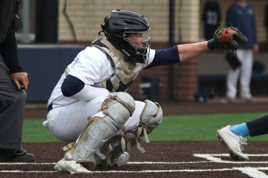 In a crouched position, senior Cody Moore catches the pitch from his teammate. 