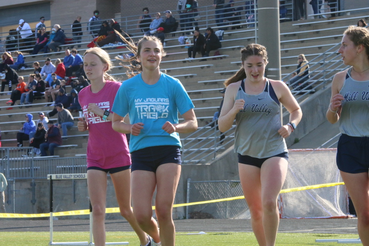 Warming up for their next event, freshman Charlotte Caldwell and seniors Logan Pfiester and Anna Brazil jog around the inside of the track
