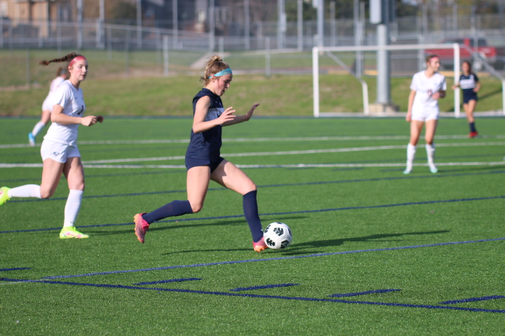 With possession of the ball, sophomore Kate Ricker prepares to pass the ball to her teammate against