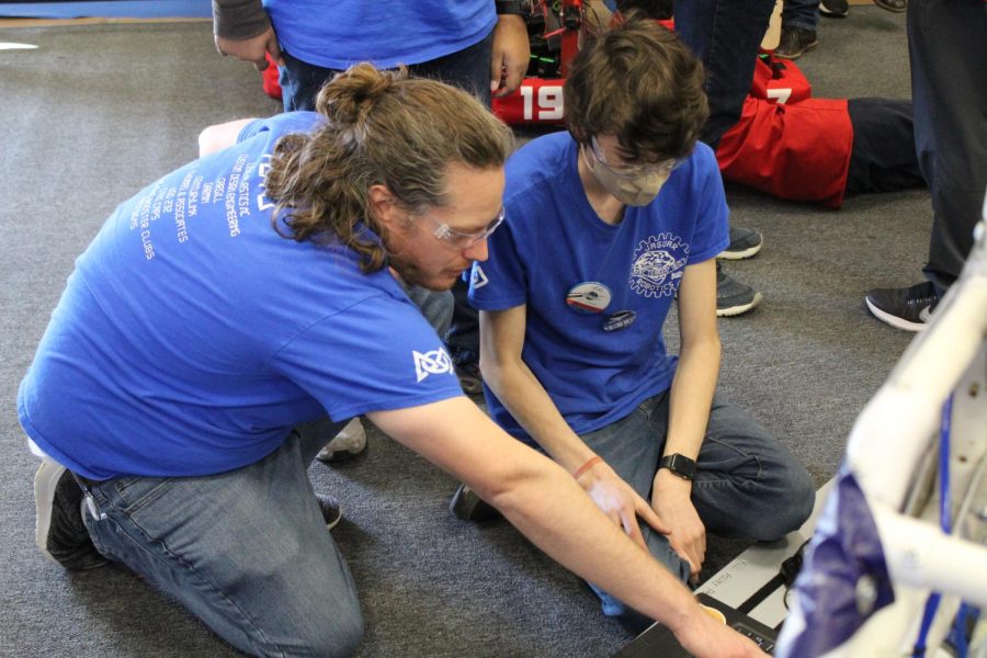 Lead mentor Neil McLeod assists De Soto sophomore Jack Williamson in editing the code for the robot Friday April 1