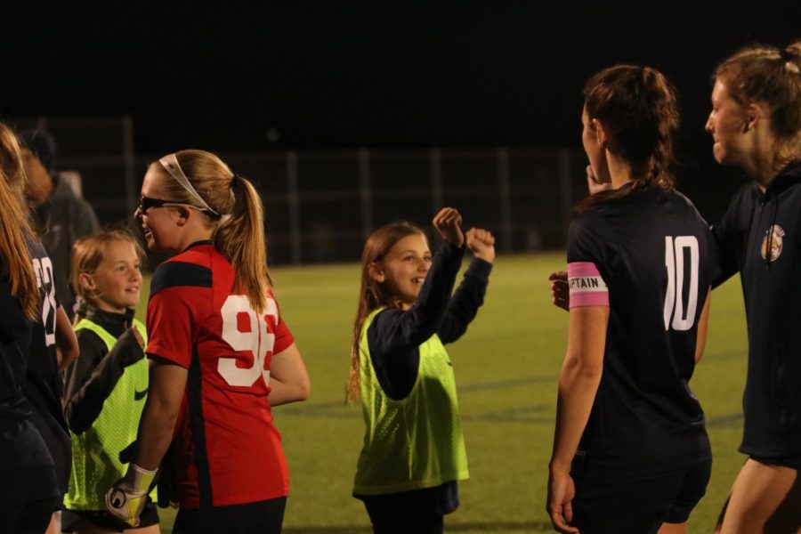 Fist bumping the ball girls, freshman Laura Hickman, junior Gracie Knight, and senior Kate Roth celebrates their victory after the game is over