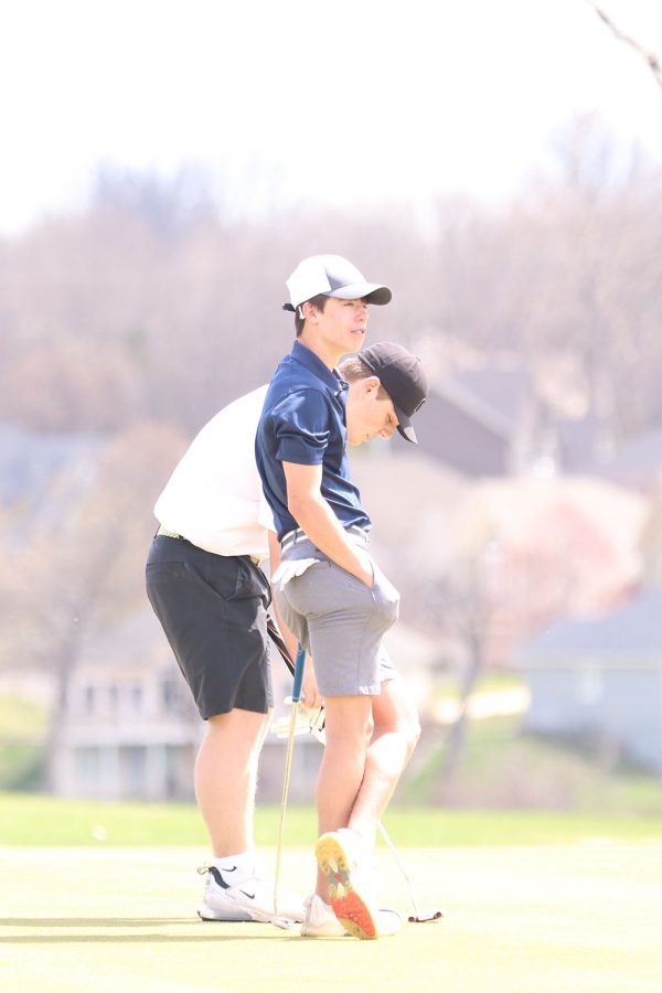 Leaning on the golf club, junior Codey Geis waits until everyone in his group hits the ball.