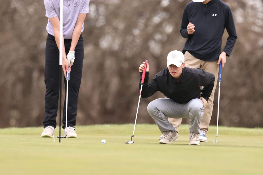 Squating on the ground, junior Matt Morgan debates on how to hit the ball.