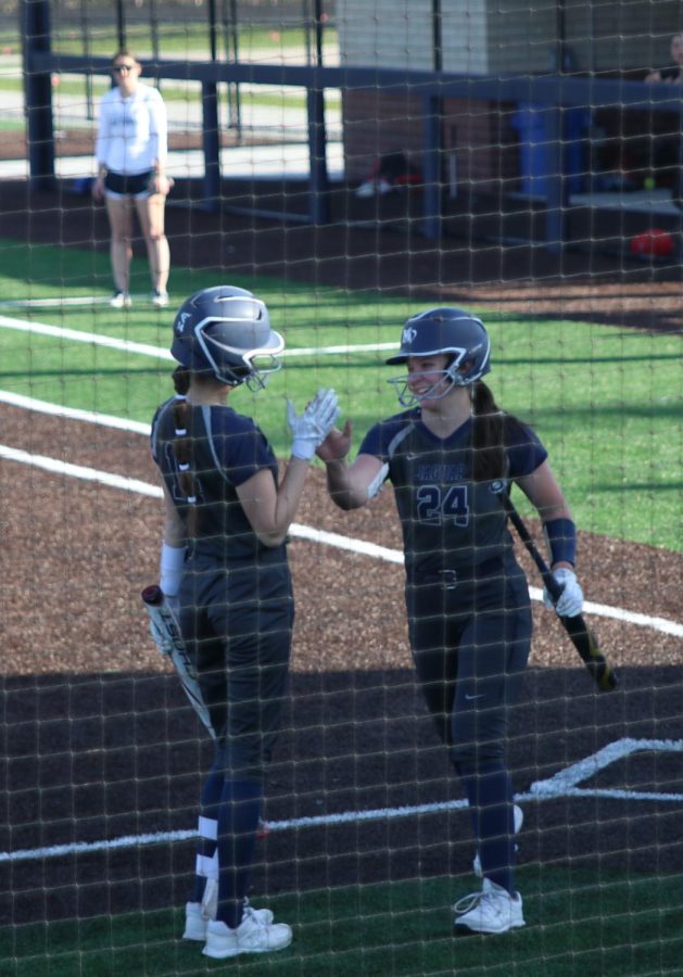 After scoring the first run of the game, junior Adisyn Hopkins gives junior Anna Stottlemyre who is up to bat