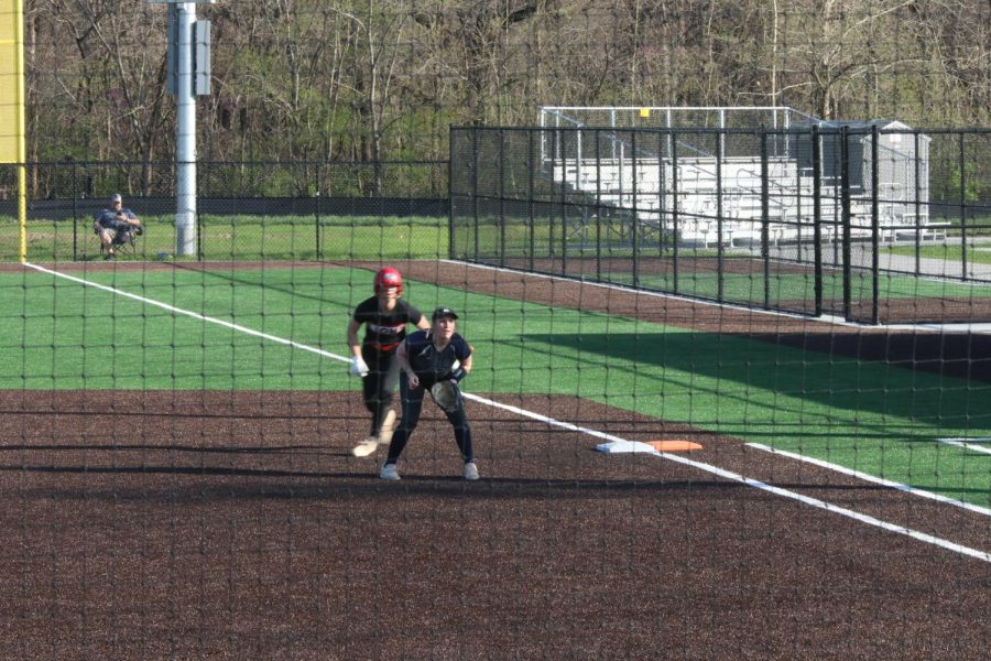 Watching the pitch closely, junior Macee Moore waits to catch the ball with an opponent from Lawrence leading off