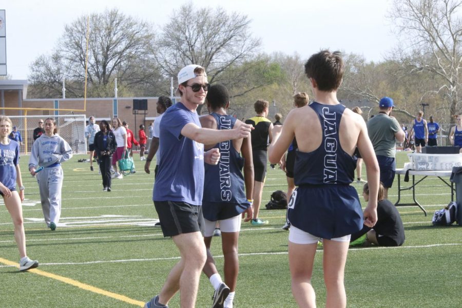 Holding out his fist, assistant track coach Brian Fitzsimmons congratulates junior Lucas Robins on his performance in the 1600 meter run.