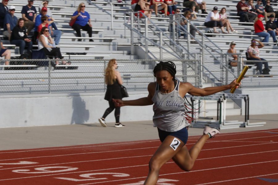 Holding out her arms, junior Savannah Harvey crosses the finish line as the anchor in the 4x100 meter relay. Harvey helped the 4x100 meter relay team take third place.