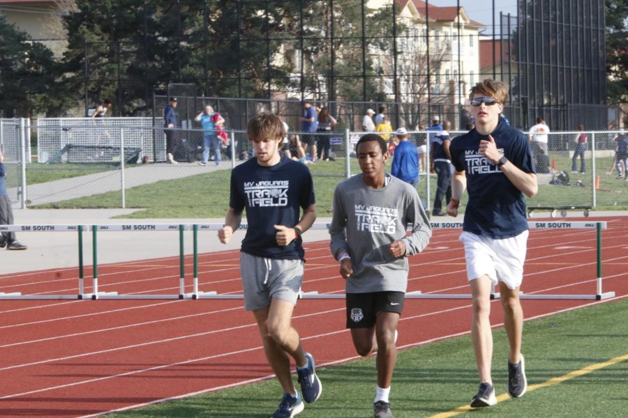 In between races, senior Chase Schieber, sophomore AJ Vega and senior Jacob McGlasson jog around the inside of the track.